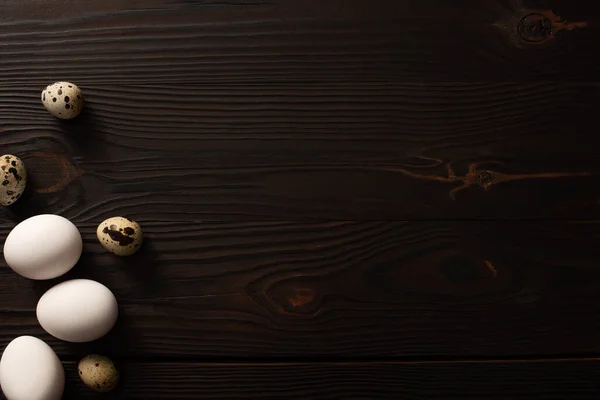 Вид зверху на білі яйця та перепелині яйця на коричневому дерев'яному фоні — стокове фото