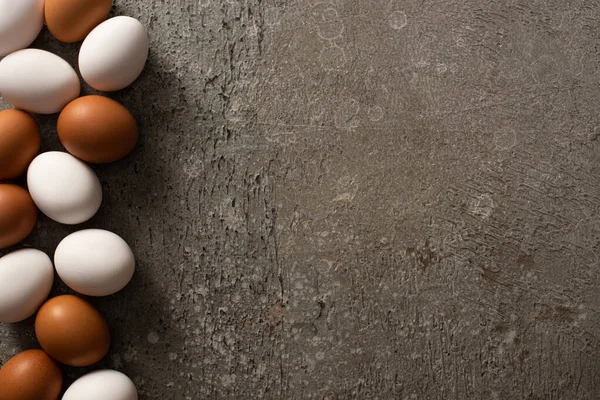 Vue de dessus des œufs de poule bruns et blancs sur fond de béton gris — Photo de stock