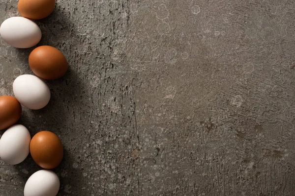 Vue du dessus des œufs de poule bruns et blancs sur fond texturé gris — Photo de stock