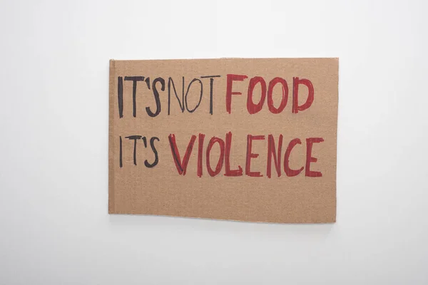 Top view of cardboard sign with its not food its violence inscription on white background — Stock Photo