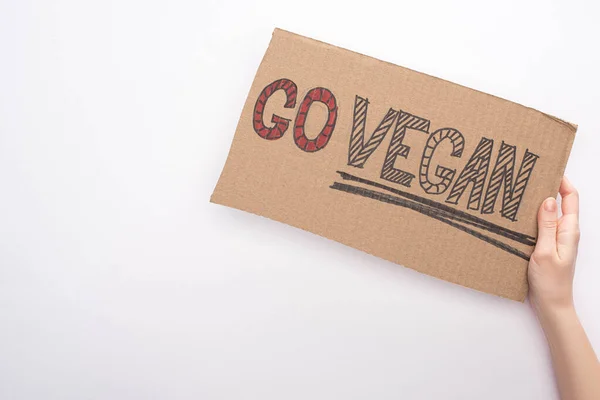 Partial view of woman holding cardboard with go vegan inscription on white background — Stock Photo