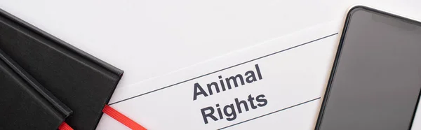 Panoramic shot of animal rights inscription, black notebooks and smartphone on white background — Stock Photo