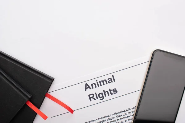 Vista superior de la inscripción de derechos de los animales, cuadernos negros y teléfono inteligente sobre fondo blanco - foto de stock