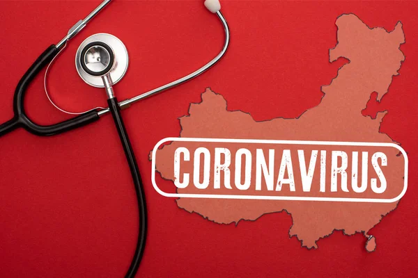 Вид сверху карты Китая со стетоскопом и иллюстрацией коронавируса на красном фоне — стоковое фото