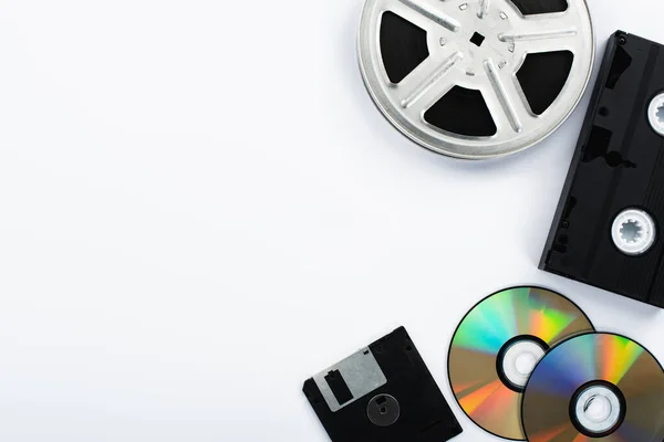 Vista superior de discos de CD, cassete VHS preto, disquete e bobina de filme no fundo branco — Fotografia de Stock