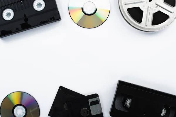 Vista superior de discos de CD, cassetes VHS, bobina de filme e disquetes em fundo branco — Fotografia de Stock