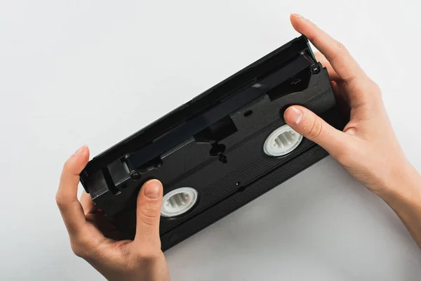 Частичный вид человека, держащего старую кассету VHS на белом фоне — стоковое фото