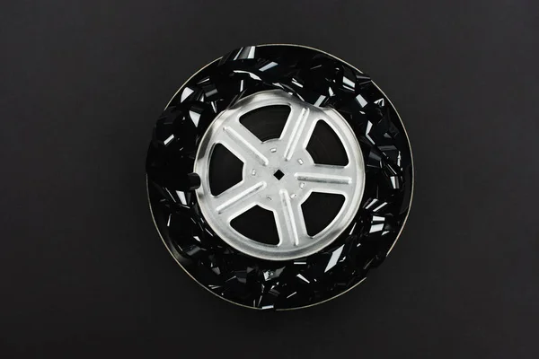 Vista superior de tira de filme preto e bobina de filme em caixa de lata enferrujada isolada em preto — Fotografia de Stock