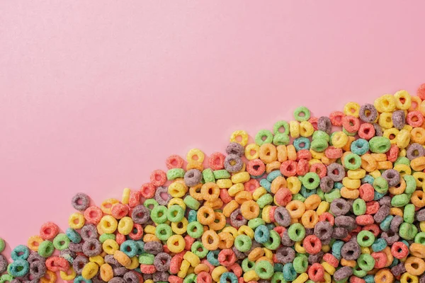 Vista superior de cereales de desayuno multicolores brillantes sobre fondo rosa - foto de stock