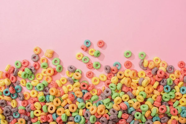 Vista superior de cereales de desayuno multicolores brillantes sobre fondo rosa - foto de stock