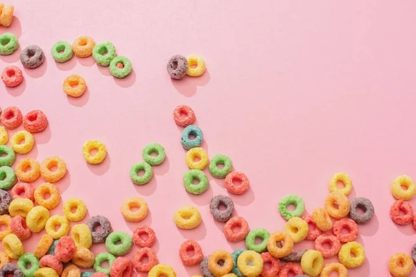 Vista superior de cereales de desayuno multicolores brillantes sobre fondo rosa - foto de stock