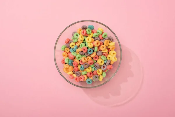 Vista superior de los cereales de desayuno de colores brillantes en un tazón sobre fondo rosa - foto de stock