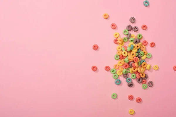 Vista superior de cereales de desayuno multicolores brillantes sobre fondo rosa - foto de stock