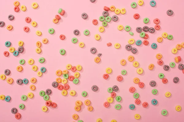 Top view of bright multicolored breakfast cereal scattered on pink background — Stock Photo