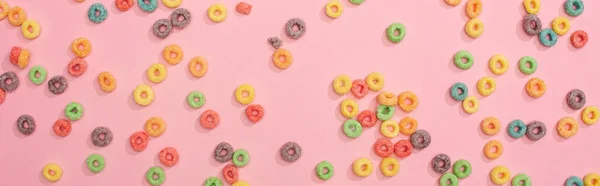 Draufsicht auf helle bunte Frühstückscerealien auf rosa Hintergrund verstreut, Panoramaaufnahme — Stockfoto