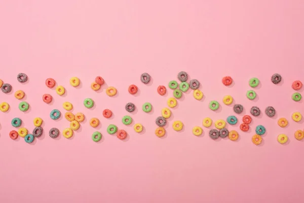 Vista superior de cereales de desayuno multicolores brillantes dispersos sobre fondo rosa - foto de stock