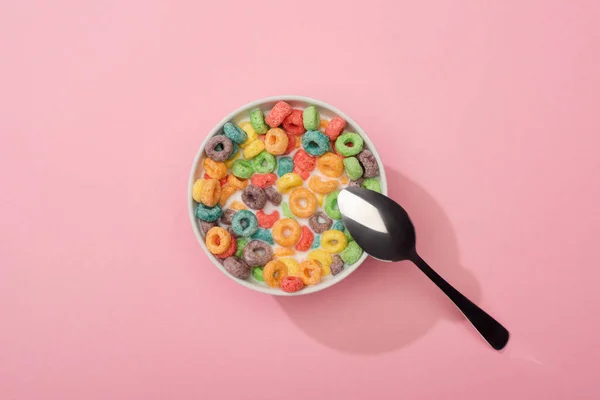 Вид зверху яскравий барвистий сніданок зерна в мисці з ложкою на рожевому фоні — стокове фото