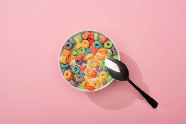 Top view of bright colorful breakfast cereal in bowl with spoon on pink background — Stock Photo