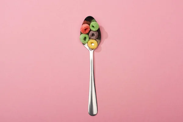 Vista superior de los cereales de desayuno de colores brillantes en cuchara sobre fondo rosa - foto de stock