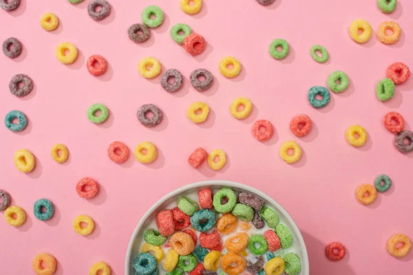 Draufsicht auf helle bunte Frühstückscerealien mit Milch in Schüssel und auf rosa Hintergrund — Stockfoto