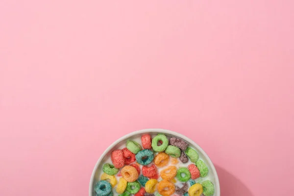 Draufsicht auf helle bunte Frühstückscerealien mit Milch in Schüssel auf rosa Hintergrund — Stockfoto