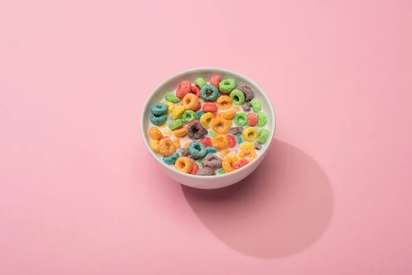 Brilhante cereal café da manhã colorido com leite em tigela no fundo rosa — Fotografia de Stock