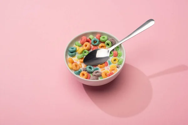 Bright colorful breakfast cereal with milk in bowl with spoon on pink background — Stock Photo