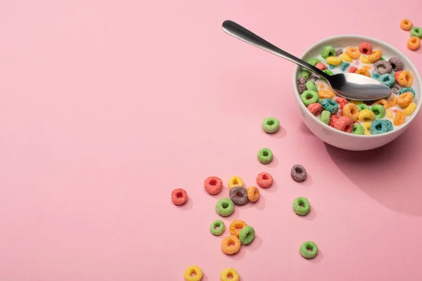 Helle bunte Frühstückszerealien mit Milch in Schüssel mit Löffel auf rosa Hintergrund — Stockfoto