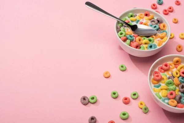 Bright colorful breakfast cereal with milk in bowls with spoon on pink background — Stock Photo