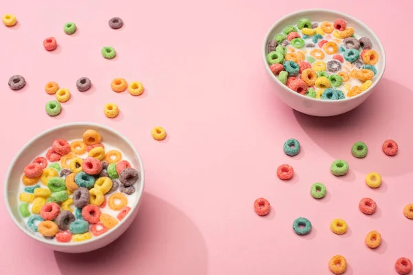 Helle bunte Frühstückscerealien mit Milch in Schalen auf rosa Hintergrund — Stockfoto