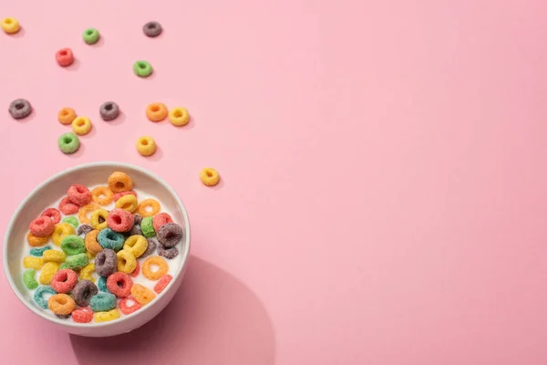 Helle bunte Frühstückscerealien mit Milch in Schüssel auf rosa Hintergrund — Stockfoto