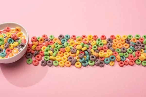 Bright colorful breakfast cereal with milk in bowl and on pink background — Stock Photo