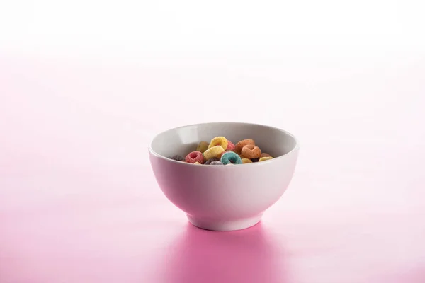 Bright multicolored breakfast cereal in bowl on pink background — Stock Photo
