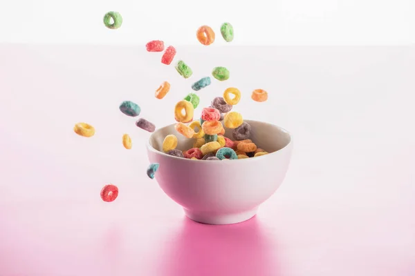 Bright multicolored breakfast cereal in bowl on pink background — Stock Photo