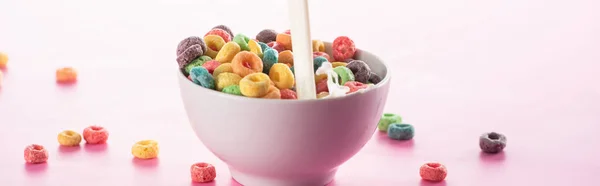 Helles, buntes Frühstückszereal in Schüssel mit eingießender Milch auf rosa Hintergrund, Panoramaaufnahme — Stockfoto