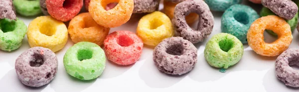 Vue rapprochée de céréales de petit déjeuner multicolores lumineuses sur fond blanc, vue panoramique — Photo de stock