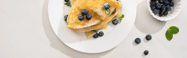 Top view of tasty crepes with blueberries and mint on plate on grey background, panoramic shot — Stock Photo