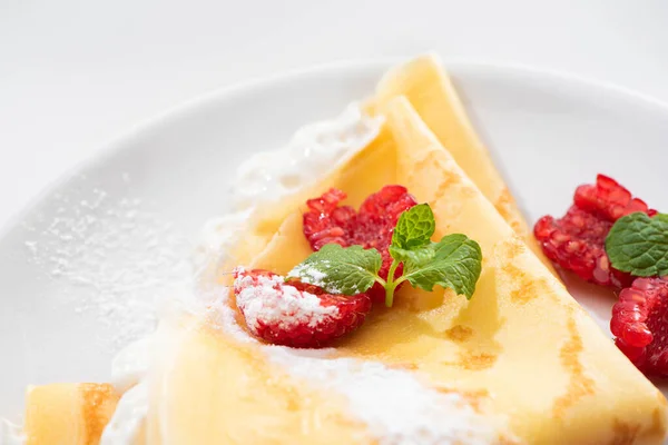 Close up view of tasty crepes with raspberries and whipped cream on plate — Stock Photo