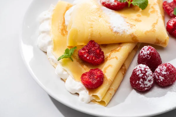 Vue rapprochée de crêpes savoureuses aux framboises et crème fouettée sur assiette — Photo de stock