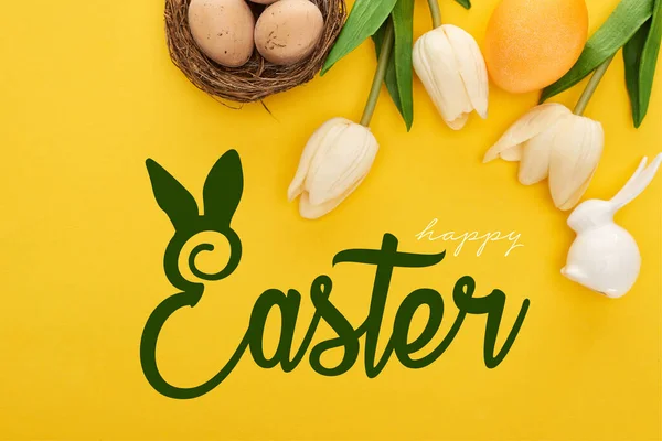 Draufsicht auf Tulpen und Hühnereier im Nest in der Nähe Osterhase auf bunten gelben Hintergrund mit frohen Ostern Illustration — Stockfoto