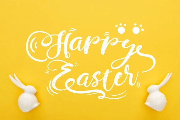 Top view of white Easter bunnies on colorful yellow background with happy Easter illustration — Stock Photo