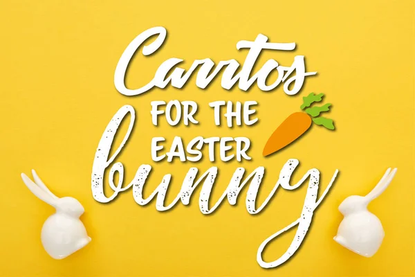 Vista superior de conejitos de Pascua blancos sobre fondo amarillo colorido con zanahorias para la ilustración del conejo de Pascua - foto de stock