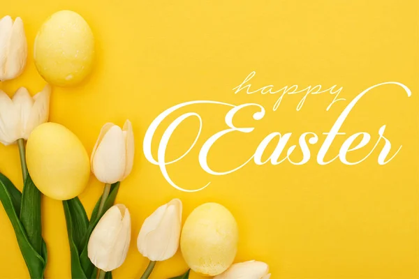 Top view of tulips and painted Easter eggs on colorful yellow background with happy Easter illustration — Stock Photo