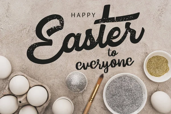 Vista dall'alto di uova di pollo, argento e brillantini dorati con pennelli sulla superficie di cemento grigio con felice Pasqua a tutti illustrazione — Foto stock