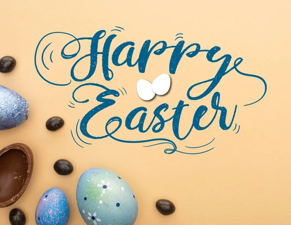 Vista superior de ovos de chocolate, codorniz e galinha com doces em fundo bege com feliz ilustração da Páscoa — Fotografia de Stock