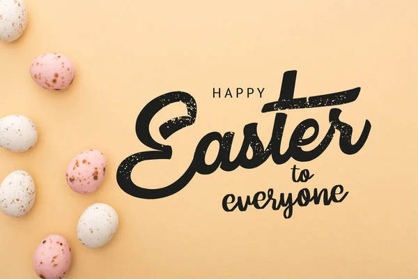 Top view of colorful quail eggs on beige background with happy Easter to everyone illustration — Stock Photo