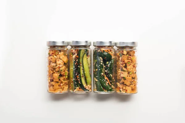 Draufsicht auf Gurken und Daikon Rettich Kimchi in Gläsern auf weißem Hintergrund — Stockfoto