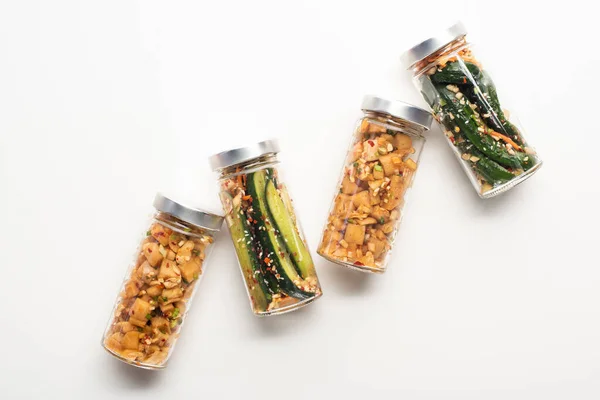 Top view of daikon radish and cucumber kimchi in jars on white background — Stock Photo