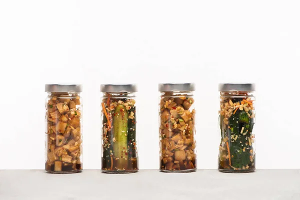 Daikon radish and cucumber kimchi in jars isolated on white — Stock Photo