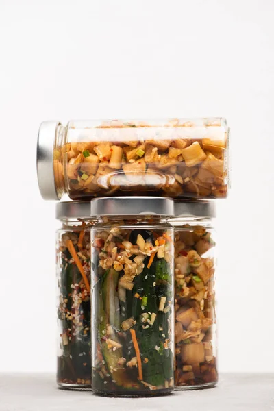 Daikon radish and cucumber kimchi in glass jars isolated on white — Stock Photo